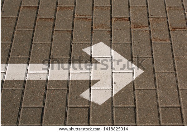Right\
pointing arrow on asphalt. Signs and\
symbols.