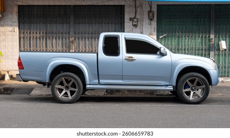 Right side view of single light blue pickup truck is parking on city street near footpath in front of people residences.