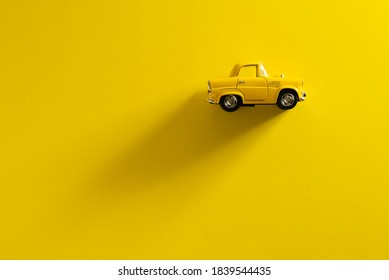 Right Side view of a Yellow toy car on a Yellow background with long and side shadow.