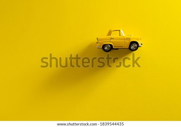 Right Side view of a Yellow toy car on a\
Yellow background with long and side\
shadow.