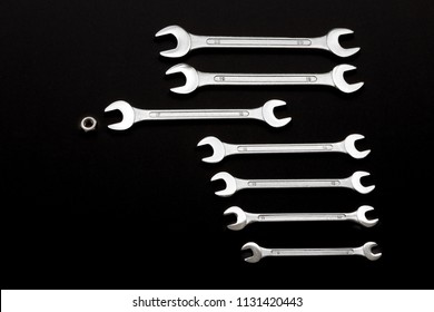 The right tool for the job. Chrome-plated set of wrenches with one female screw on dark background.