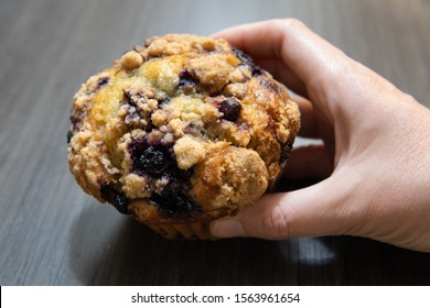 Right woman's hand picking up blueberry muffin. Breakfast, desert food concept.