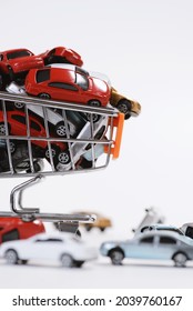 Right-view colorful toy cars in the shopping cart and on the floor on white background.