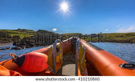 Rigid inflatable boat out on sea near an island on a sunny day