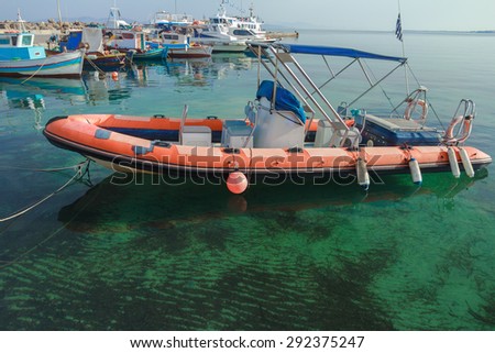 Rigid-hulled inflatable boat is floating on calm blue transparent sea water of Greek Kos island