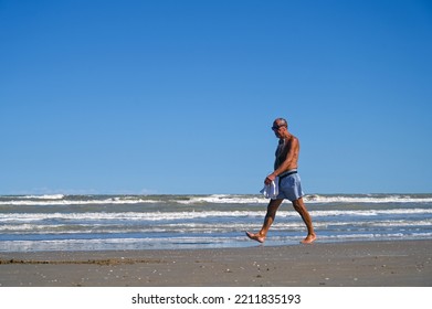 Rimini, Italy, September 2022: Man Walking On Sandy Beach Near Sea. Elderly Man Enjoy A Walk By The Sea In Summer.