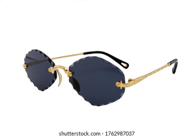 Rimless sunglasses and dark blue rhomboid shaped lenses   gold thin frames isolated white background  Side view 