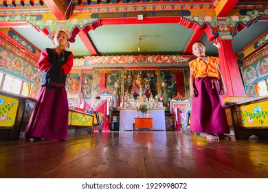 Rinchenpong, Sikkim, India - 17th October 2016 : Two young boy Lamas standing inside prayer room at Rinchenpong monastery with decorated murals on the walls. Shot from below.