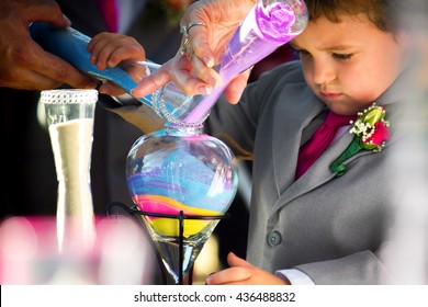 A Ring Bearer, Who Is The Son Of The Bride, Pours Colored Sand In The Unity Ceremony During A Wedding.