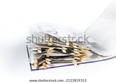Ring binder or document folder with transparent punched pockets full of receipts closed with wooden clothespins, accounting, tax calculation, office management, selected focus, narrow depth of field