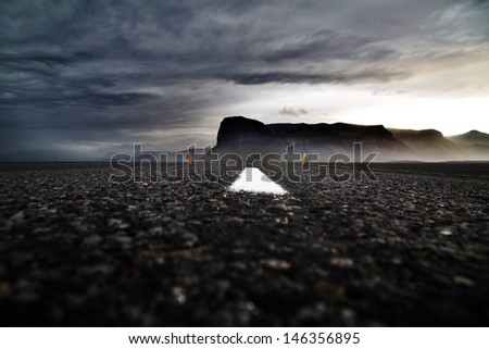 ring road Iceland dramatic Icelandic landscape dark clouds white roadmarks and fog covered mountains overcast sky beautiful travel destination mysterious mood ringroad is your tourism guide to explore