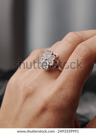 A ring in the shape of a four-leaf clover with precious stones on the finger. An elegant decoration that emphasizes style and luxury.