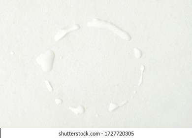 A ring of water droplets on a white wooden table formed by a wet cup after being lifted from the surface. Circle of water pattern stains caused by water on the bottom or base of a cold drinking glass.