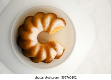 Ring-shaped Morning Cake (Bundt Cake / Gugelhupf), With A Piece Cut Off, In The Rays Of Rising Sun. Optimistic Image Similar To Pie Chart Or Infographics Diagram For A Concept Of Successful Business