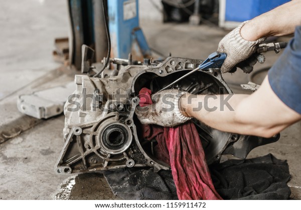 rinse\
clutch unit after the leaking of engine oil. Change and repair\
clutch, drive axle. working underneath a lifted car. Professional\
mechanic work maintenance car. Garage car\
service.