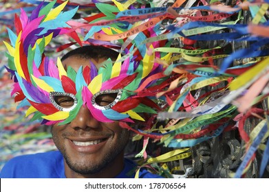 Rio Carnival Scene Features Smiling Brazilian Man In Colorful Mask With Wish Ribbons