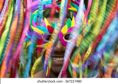 Rio Carnival Scene Features Smiling Brazilian Man In Colorful Mask With Streamers In Motion Blur