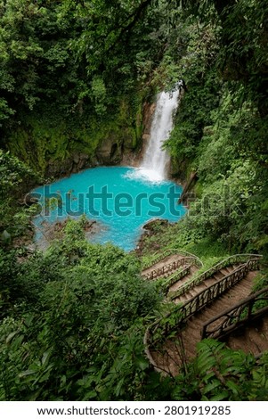 Rio celeste waterfall creating a turquoise lagoon, surrounded by lush tropical rainforest and natural stairs
