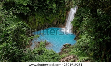 Rio celeste waterfall dropping into a vivid blue natural pool surrounded by dense rainforest
