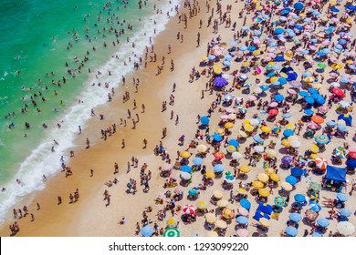 Rio de Janeiro, Brazil, aerial view of Copacabana Beach showing colourful umbrellas and people bathing in the ocean on a summer day. Tropical travel and vacation concept.