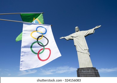 RIO DE JANEIRO, BRAZIL - CIRCA MARCH, 2015: Olympic and Brazilian flags hang in clear blue sky next to the statue of Christ the Redeemer. [Illustrative editorial]