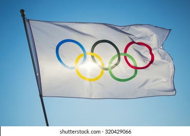RIO DE JANEIRO, BRAZIL - FEBRUARY 12, 2015: An Olympic flag flutters in the wind backlit against bright blue sky.