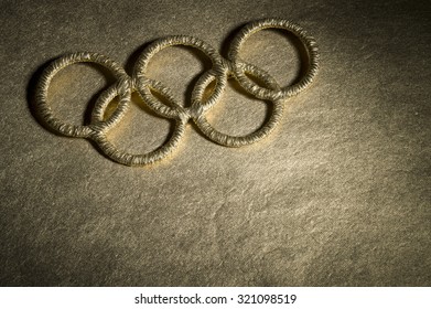 RIO DE JANEIRO, BRAZIL - FEBRUARY 3, 2015: Gold Olympic Rings Symbol Spotlit On Shiny Golden Background.