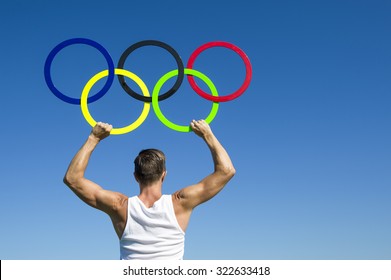 RIO DE JANEIRO, BRAZIL - FEBRUARY 4, 2015: Athlete holds Olympic rings aloft against bright blue sky.