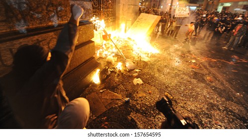 RIO DE JANEIRO, BRAZIL - OCTOBER 08: Black Bloc protesters throw molotov cocktails against the Chamber of Counselors municipal building during schoolteachers demonstrations demanding better wages on October 8th, 2013 in Rio de Janeiro, Brazil. - Shutterstock ID 157654595