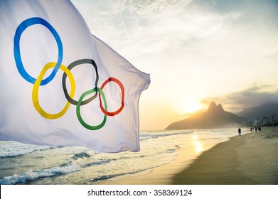 RIO DE JANEIRO, BRAZIL - OCTOBER 27, 2015: An Olympic flag flutters in the wind in front of the sunset skyline at Ipanema Beach.