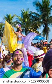 RIO DE JANEIRO - FEBRUARY 07, 2016: A Young Brazilian Woman In Brightly Colored Carnival Costume Makes Her Way On Stilts Through The Crowd Celebrating At A Street Party In Ipanema.