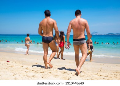 RIO DE JANEIRO - FEBRUARY 08, 2015: Young Brazilian men wearing a style of swimwear known locally as "sunga" walk on the shore of Ipanema Beach.