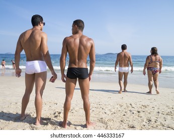 RIO DE JANEIRO - FEBRUARY 08, 2015: Muscular young Brazilian men stand on Ipanema Beach in swimwear in a style known locally as "sunga".