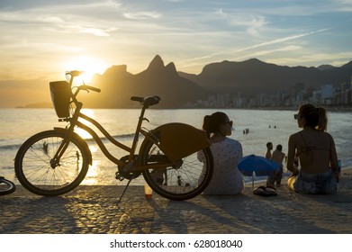 RIO DE JANEIRO - FEBRUARY 22, 2017: Two young women sit watching the sunset at Arpoador, a popular summertime activity for locals and tourists.