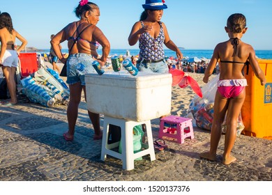 RIO DE JANEIRO - FEBRUARY 28, 2017: Brazilian Beach Vendors Selling Beer From A Styrofoam Cooler Stand With A Child On The Ipanema Boardwalk.