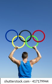 RIO DE JANEIRO - FEBRUARY 4, 2015: An athlete in blue holds Olympic rings aloft against bright blue sky.