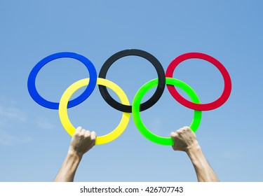 RIO DE JANEIRO - MARCH 15, 2016: Hands of athlete hold Olympic rings aloft in blue sky in celebration of the city hosting the Summer Games.
