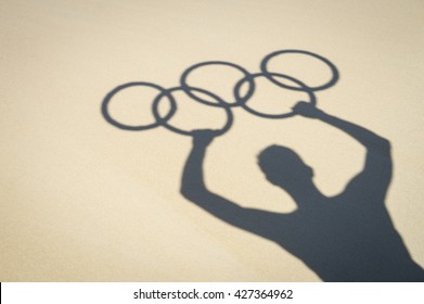 RIO DE JANEIRO - MARCH 20, 2016: Shadow silhouette on the sand of a man holding Olympic rings in celebration of the city hosting the Summer Games.