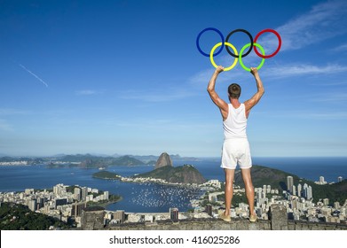 RIO DE JANEIRO - MARCH 21, 2016: An athlete holds Olympic rings under bright blue sky above the city skyline in anticipation of the city hosting the Summer Games.