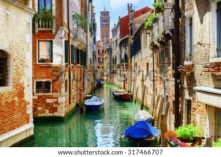 The Rio di San Cassiano Canal with boats and colorful facades of old medieval houses in Venice, Italy. Bell-tower of San Cassiano (Church of Saint Cassian) is visible in background.
