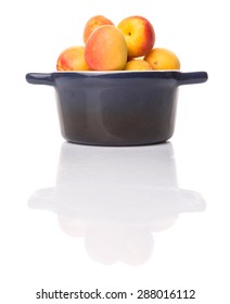 Ripe apricot fruits in a bliue pot over white background
