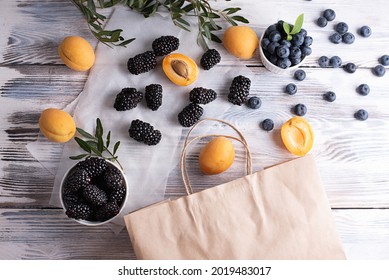 Ripe Apricots, Blueberries, Blackberries On A White Wooden Background, Summer Berries Spilled From A Paper Bag, Apricots, Blueberries, Healthy Food.