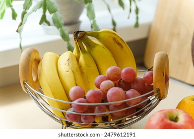 Ripe bananas and a bunch of grapes in a fruit basket on the table. Close-up. - Powered by Shutterstock