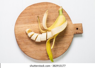Ripe bananas and a sliced on white wooden cutting board, top view  - Powered by Shutterstock