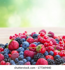ripe of  berries on wooden table in garden  - blackberry, raspberry , red currant and blueberry