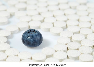 Ripe Blueberries Surrounded By Pills On All Sides. Concept: Natural Vitamins. Close Up.