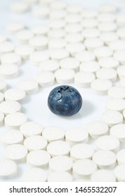 Ripe Blueberries Surrounded By Pills On All Sides. Concept: Natural Vitamins. Close Up.