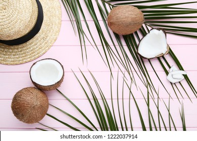 Ripe coconuts with palm leafs and hat on pink wooden table - Powered by Shutterstock