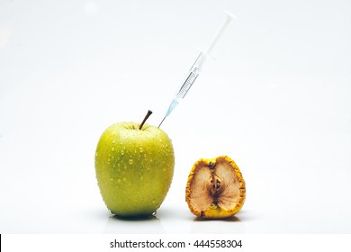 Ripe fresh apple fruit with water drops and wrinkled peel getting rejuvenation procedure by syringe needle isolated on white background. Aging concept. Botox injection concept