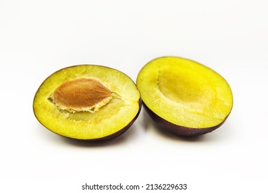 Ripe fresh organic plum cut into halves isolated on white background. - Shutterstock ID 2136229633